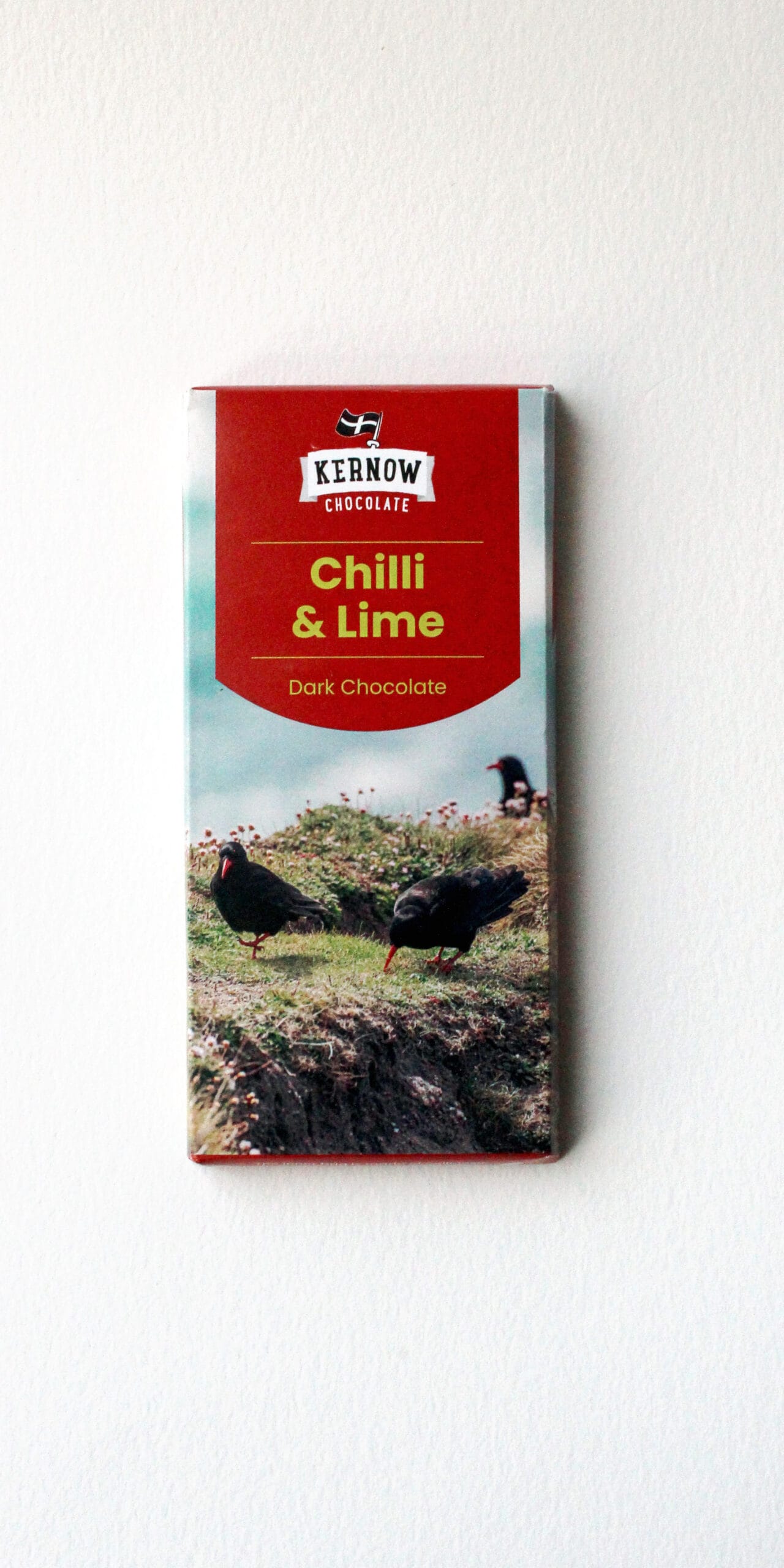 Kernow Chocolate Chilli & Lime dark chocolate bar in red packaging with a scenic coastal image, rectangular block on a white background